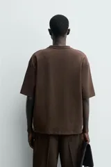 Remera de corte relajado confeccionada en tejido compacto de mezcla de algodón con elasticidad. Presenta cuello redondo, manga corta y un bolsillo frontal de plastrón.