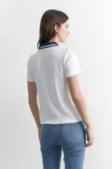 Remera blanca de manga corta con cuello polo azul marino y cierre metálico.