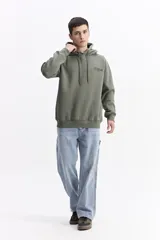 Canguro con capucha color verde oliva, de corte regular, con estampado gráfico multicolor en la espalda que incluye texto y formas abstractas.