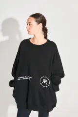 Buzo oversize negro de frisa con cuello redondo, hombros caídos, bolsillos delanteros y estampa serigráfica en delantero y espalda.