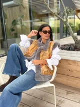 Chaleco de piel sintética en color gris, con diseño reversible. El interior presenta un forro de tela color mostaza con estampado floral bordado. Posee un corte holgado y sin mangas.