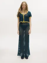 Conjunto de tejido calado color azul petróleo con detalles en amarillo. Incluye un cárdigan corto con botones y una falda larga recta con pretina elástica.