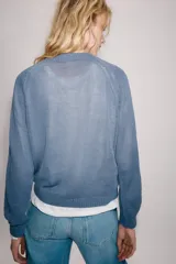 Sweater de punto color beige con cuello redondo, manga larga y cierre frontal parcial con botones. Presenta terminaciones en rib en cuello, puños y dobladillo.