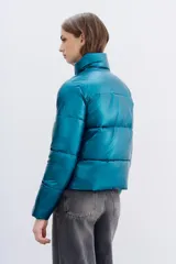 Campera puffer metalizada color verde petróleo, con cuello alto, cierre frontal y bolsillos con cierre.