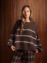 Buzo corto de tejido de punto en color negro, con diseño de textura en relieve y líneas horizontales blancas. Presenta cuello redondo y mangas largas con puños ajustados.