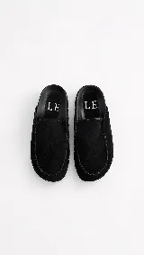 Zuecos tipo mule de cuero gamuzado negro, con plataforma forrada y detalle de tachas plateadas en el contorno. Presentan una plantilla con el logo bordado.