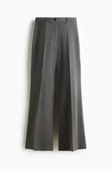 Pantalón sastrero de tiro alto con corte acampanado y pliegues frontales. Cuenta con cierre de botón y bolsillos decorativos.