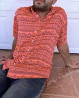 Camisa de seda color naranja con estampado geométrico en negro, de corte recto y manga corta.