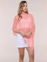 Poncho liviano de tejido de punto fino calado, color blanco, con silueta asimétrica envolvente, escote bote drapeado y mangas integradas estilo capa.