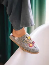 Pantuflas de fieltro color gris, abiertas en el talón, con delicados bordados florales multicolores en el empeine y detalle de trenza de yute en la suela.