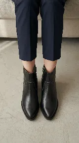 Bota corta tipo chelsea de cuero negro, con panel lateral texturizado y taco cuadrado bajo.