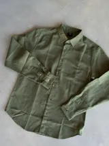 Camisa de manga larga color verde militar, con cuello clásico y cierre frontal de botones. Confeccionada en un tejido tipo lino.