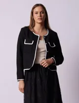 Chaqueta de tweed negra marca Nanette, con escote a la base, abertura central con botones, bolsillos delanteros, aplique de botones perlados en los puños, ribete en contraste blanco y forro interno.