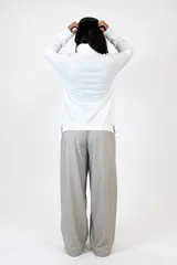 Polera de cuello alto y manga larga, confeccionada en algodón suave de color blanco, con diseño de corte recto y aberturas laterales en el ruedo.