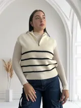 Chaleco de punto color crudo con rayas horizontales negras, cuello polo con cierre metálico y corte holgado.