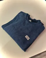 Buzo azul con efecto nevado gastado, corte oversized y cuello redondo.