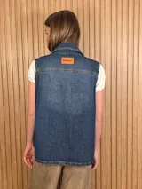 Chaleco de denim 100% algodón en color negro gastado, con cuello camisero, cierre frontal de botones metálicos y bolsillos delanteros con solapa.