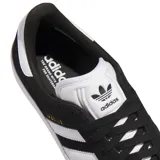 Championes Adidas Gazelle ADV, color negro con las icónicas tres bandas laterales en blanco y suela de goma blanca. Presenta el nombre del modelo en dorado en el lateral y detalles en blanco en el talón y la lengüeta.