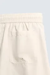 Bañador de hombre negro, largo hasta la rodilla, con acabado aterciopelado. Presenta cintura elástica ajustable con cordón, bolsillos laterales y un bolsillo trasero de plastrón. Incluye forro interior.