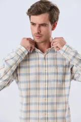 Camisa de manga larga de lino y algodón, con estampado a cuadros en tonos beige, blanco y celeste, cuello camisero y cierre frontal con botones.