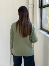 Sweater de punto color verde, de corte recto y holgado, con cuello redondo y dos bolsillos frontales aplicados.