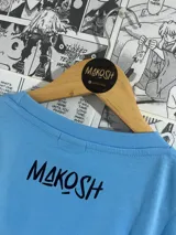 Remera celeste con estampa gráfica de Mr. Meeseeks y calaveras con la frase "Existence is pain".