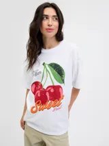 Remera de cuello redondo y mangas cortas, con calce holgado y estampa frontal de cerezas con texto decorativo.