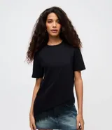 Remera de algodón con cuello redondo, mangas cortas y corte alargado. Presenta un diseño asimétrico en el ruedo con detalle de encaje aplicado en uno de los lados.
