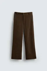 Pantalón de corte wide fit confeccionado en pana de algodón color marrón oscuro. Presenta bolsillos frontales, bolsillos traseros de vivo con botón y cierre frontal con cremallera y botón.