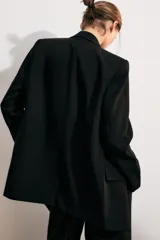 Blazer marrón de cuello solapa con muescas, manga larga y bolsillos de vivo con solapa. Cierre frontal con un botón.