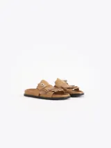 Sandalias planas color tostado de cuero vacuno, con capellada adornada con flecos y una tira con hebilla metálica.