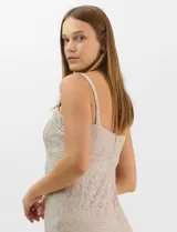 Vestido largo de encaje color beige, con escote recto decorado con pedrería y perlas, tirantes anchos y tajo lateral en la falda.