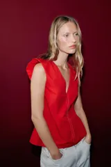Top rojo de popelín con escote en V pronunciado, mangas sisa y pespuntes en contraste. Cuenta con tirantes finos cruzados y lazada en la espalda.