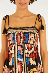 Vestido largo multicolor con estampado floral y geométrico, de corte fluido, con escote cuadrado fruncido y breteles finos ajustables con borlas colgantes en los extremos.