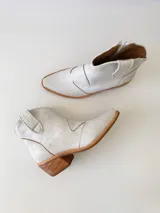 Botas texanas de cuero color gris claro, con caña baja, puntera cuadrada y taco de madera.