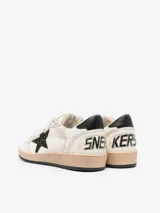 Zapatillas deportivas de cuero color blanco con detalles en negro y estrella de glitter color borgoña.