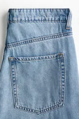 Jean wide leg de tiro alto en denim rígido de lavado claro, con diseño de cinco bolsillos y perneras amplias y holgadas.