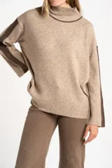 Polera oversize color beige melange, de punto con mangas largas y detalles de franjas marrones en las mangas y cuello.