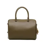 Cartera tipo bauletto de Marc Jacobs, confeccionada en cuero de cordero color verde oliva. Presenta un diseño estructurado con detalles drapeados en el frente, asas superiores y una correa de hombro ajustable y extraíble. Incluye herrajes metálicos dorados y un dije decorativo en la parte frontal.