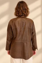 Camisa de cuero color marrón, de corte recto y largo medio, con cuello redondo a la base, cierre frontal con broches metálicos y bolsillos aplicados en los laterales.
