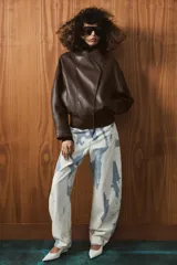 Jeans de tiro medio con corte barrel, confeccionados en algodón con estampado tipo tie-dye en tonos azul y blanco. Presentan diseño de cinco bolsillos, trabillas en la cintura y cierre frontal con cremallera y botón.