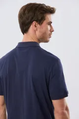 Remera polo de manga corta en color azul melange, con cuello camisero, cierre frontal de dos botones y pequeño bordado en el pecho.