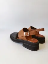 Sandalias de cuero color negro y marrón con textura tipo cocodrilo, con hebilla ajustable y suela track. Fabricadas en Uruguay.
