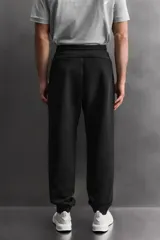 Pantalón jogger de entrenamiento, corte regular fit, color verde oliva oscuro. Confeccionado en tejido técnico compacto de algodón con elasticidad y efecto neopreno. Presenta cintura elástica ajustable con cordón blanco, bolsillos frontales y un bolsillo lateral con cierre de cremallera. El bajo termina en puño.