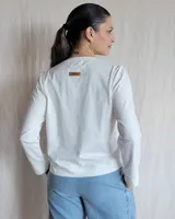 Remera de algodón color blanco, con escote en V y detalle de pespuntes decorativos en color beige. Presenta mangas largas y un corte recto con aberturas laterales en el ruedo.