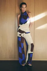 Top de cuello halter con hombros descubiertos, espalda descubierta, detalle de drapeado lateral y bajo asimétrico.