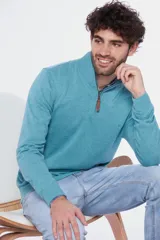 Buzo liso de punto fino en hilo de algodón color azul marino, con cuello alto y cierre frontal parcial con detalle de tirador de cuero.