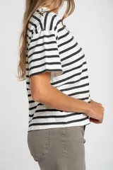 Remera de corte oversize confeccionada en algodón lavado, con diseño de rayas horizontales en color negro sobre fondo crudo, cuello redondo y mangas cortas.