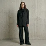 Pantalón de vestir negro con diseño de rayas diplomáticas blancas, corte recto y holgado, con bolsillos laterales.