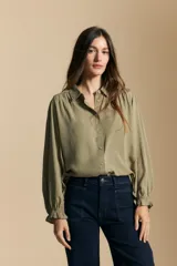 Camisa de manga larga color celeste, con cuello clásico, cierre frontal con botones y puños elastizados con volados. Presenta un diseño fluido con detalle de vainilla en la espalda.